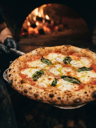 Gros plan sur une pizza croustillante sortant d'un four à bois, mozzarella fondante, basilic frais, lumière chaude du feu, tons saturés.