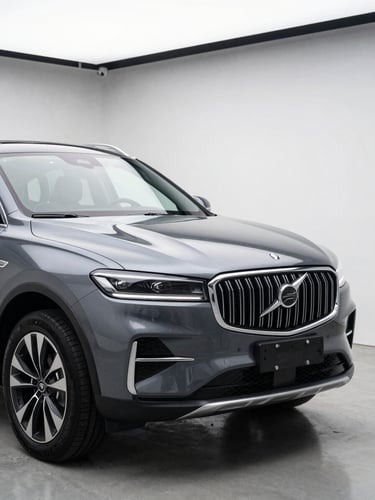 Close-up three-quarter front view of a dark metallic SUV in a minimalist studio bay, bright white overhead lighting reflecting off the hood, clean concrete floor, no background distractions, precision automotive photography