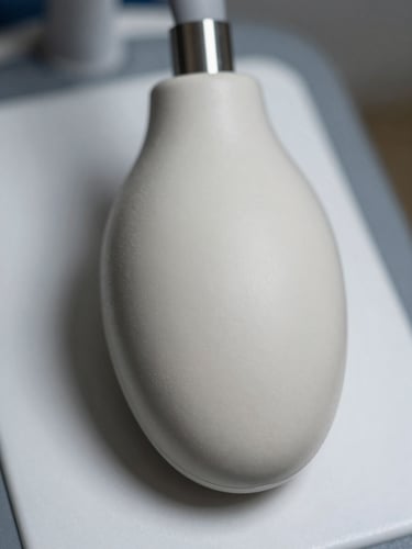 Extreme close-up of a convex ultrasound probe head resting on a white clinical surface, curved transducer face filling the lower frame, clinical overhead lighting, fine surface texture and cable connector visible at top, no hands, no branding