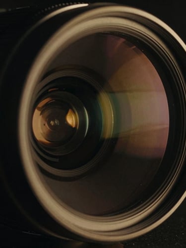 Extreme close-up of an anamorphic lens with a golden rim light reflection, deep chiaroscuro shadows, cinematic film photography, 35mm.