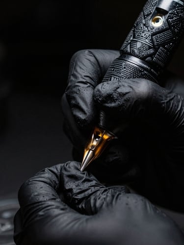 Macro close-up of a professional tattoo artist's hand wearing a black nitrile glove, holding a sleek wireless tattoo machine, precise gold needle details, dramatic chiaroscuro lighting, deep black background.