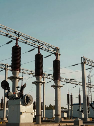 Wide-angle, structured shot of industrial high-voltage distribution infrastructure with cool-toned lighting, emphasizing geometric precision.