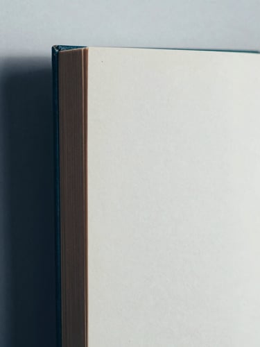 Close-up of a vintage book spine and clean paper texture, muted tones, soft diffused daylight, 35mm film grain