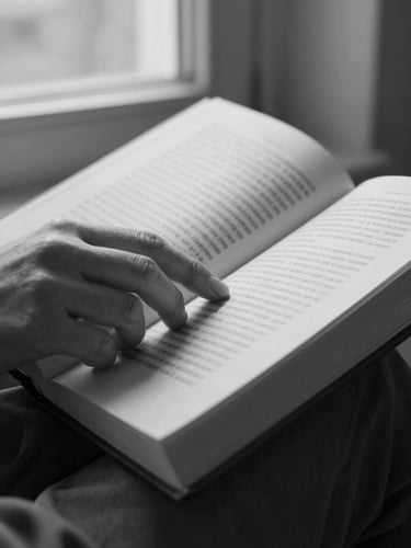 Extreme close-up of a woman's hands holding an open book, fingers resting on the page, photographed in black and white under soft north-facing window light, ink visible on the open pages, fabric sleeve at the wrist edge of frame, quiet and still