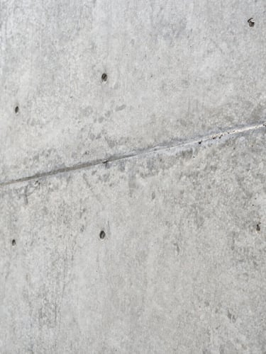 Extreme close-up of a flawless architectural concrete wall showing raw aggregate texture and sharp formwork tie-rod holes.