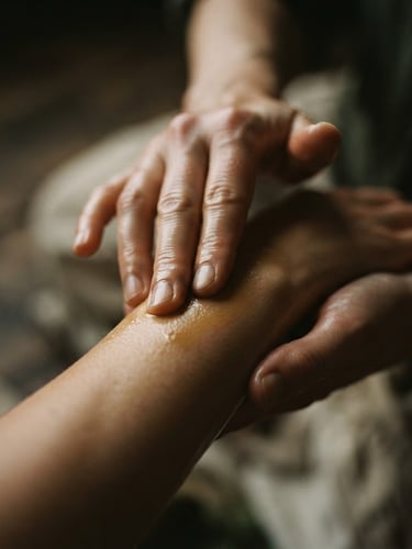 Close-up of hands gently applying botanical oils to skin, soft low-key ambient light, muted earth tones, shallow depth of field, 35mm
