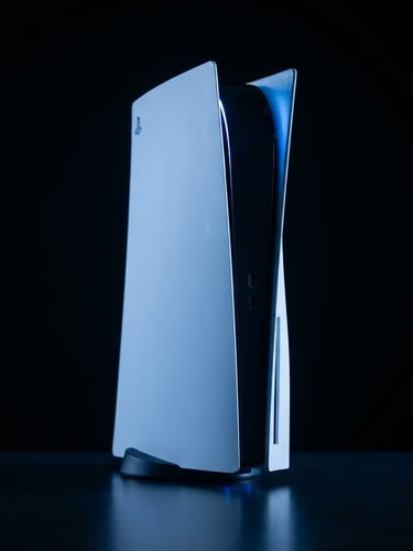 Sleek PlayStation 5 console standing vertically, dramatic blue neon studio lighting, dark high-contrast background, sharp focus, 8k resolution