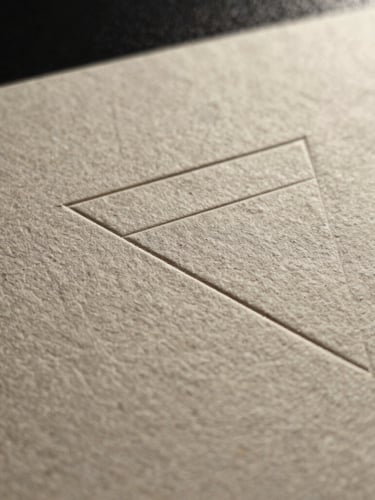 A macro shot of premium textured heavy paper stock with a sharp debossed geometric line, side-lit by precise studio key lighting.