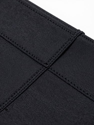 Macro detail shot of a black technical compression fabric weave, showing double-stitched seams and precise texture, bright cool-toned studio light, sharp focus