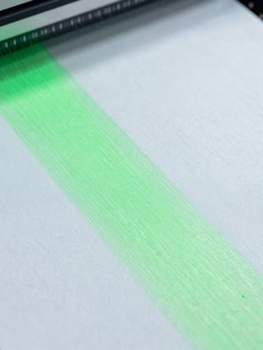 Macro detail shot of high-speed sublimation printing on technical white polyester fabric, neon green dye absorbing into fibers, bright cool-toned studio light