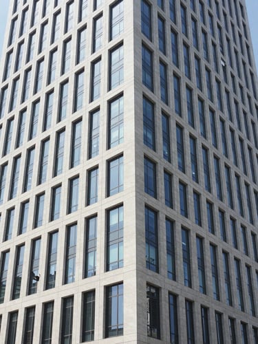 Crisp commercial photography of a modern high-rise office building exterior in daylight, clean architectural lines, wide angle 35mm