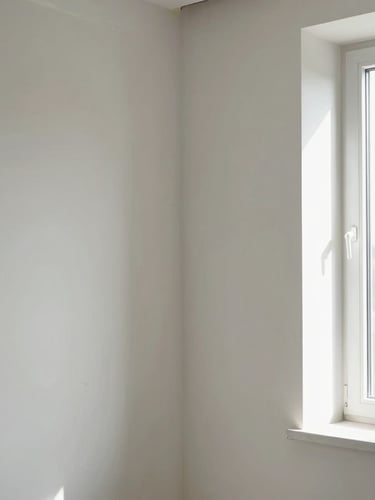 Bright architectural interior shot of a finished drywall joint, perfectly smooth plaster surface illuminated by soft daylight streaming from a side window.