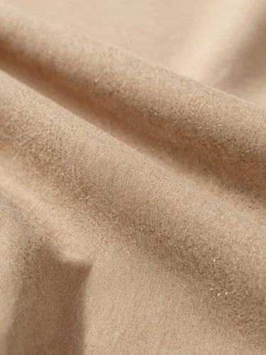 Macro close-up detail of premium breathable cotton fabric drape and fine stitching, soft natural overcast light, warm sand tones, 35mm lens