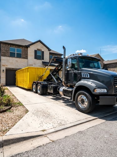 Wide-angle, low-angle heroic shot of a clean roll-off dumpster truck backed into a residential driveway, a bright safety-yellow dumpster clearly visible, harsh Texas sunlight, high-contrast charcoal and yellow tones, sharp focus.