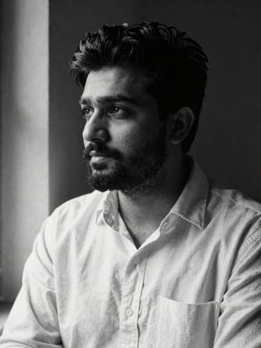 Stark black and white portrait of Samir Singh in quiet thought, high-contrast side-lit window light, 35mm film grain, rich paper texture background, looking slightly off-camera.
