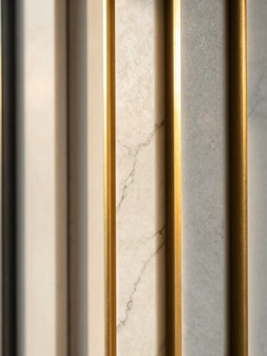 Tight, high-contrast detail shot of premium architectural materials, polished white marble and gold brass accents under warm natural window light, 35mm lens