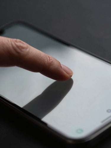 Extreme close-up of a finger resting on an Android device screen, a minimal dark-UI app visible under soft overcast studio light, sharp focus on the fingertip and glass surface, dark background