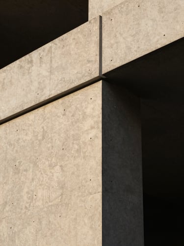 A close-up of a minimalist modern concrete and steel architectural structure connecting at a precise angle, warm side lighting, dark background.