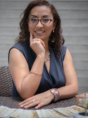 Mujer profesional de tarot sentada en una mesa con una baraja de tarot 