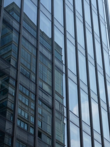 Macro shot of abstract geometric glass reflections on a modern corporate skyscraper, cool daylight, sharp focus, blue and slate tones.