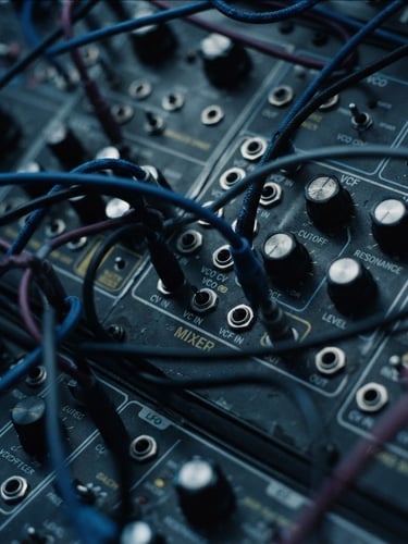 Macro close-up of analog synthesizer patches with patch cables, moody atmospheric photography, low-key studio lighting, deep charcoal and cool blue tones, macro lens, 35mm