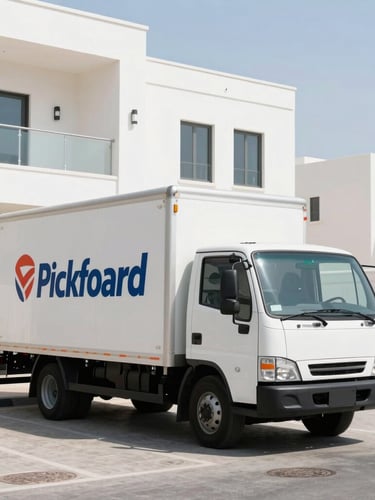 A clean, branded Allied Pickfoard moving truck parked in front of a modern white villa in Umm Al Quwain under bright UAE daylight, crisp shadows