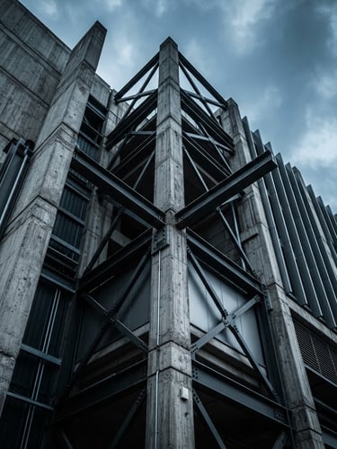 Low-angle architectural crop of a modern concrete and steel building structure under a high-contrast cool overcast sky, industrial architectural photography style.