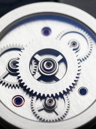 Extreme macro detail of a precision mechanical watch movement, gears aligned in perfect symmetry, high-contrast natural light with deep shadows, navy and white tones