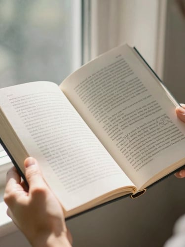 Hands holding an open hardcover book with highly legible text, warm morning sunlight filtering through a window, 35mm photography