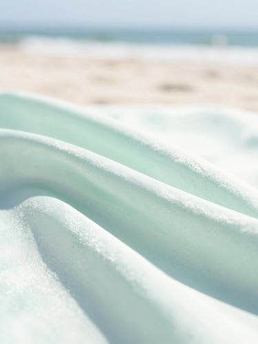 Close-up of soft silk fabric folds in soft seafoam green, bright high-key coastal daylight, shallow depth of field, 35mm