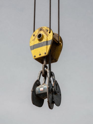 Industrial documentary photography, close-up of heavy rigging gear and steel shackles under hard direct daylight, high-contrast desaturated tones, 35mm lens.
