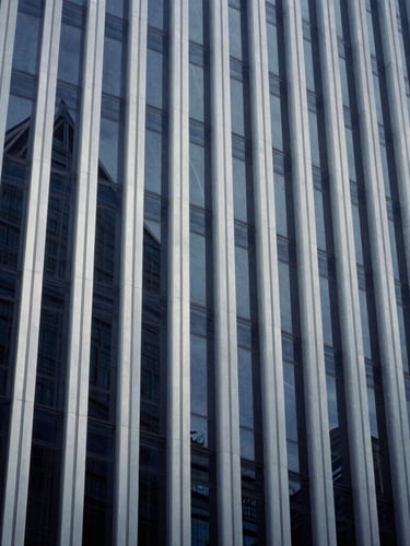 Abstract architectural lines of a modern corporate high-rise building reflecting cool daylight, sharp angles, deep navy and silver tones, 35mm