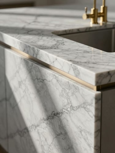 Close-up of a marble kitchen island, natural morning light casting soft shadows across the vein alignment, sharp details of custom brass fixtures.