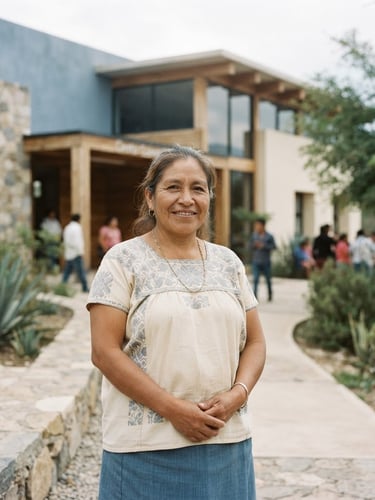 A medium-wide environmental portrait of a local community leader in warm overcast daylight, standing outside a newly constructed educational center, muted blue tones, 35mm lens, documentary style.