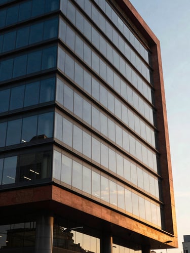 Modern office building facade in San Isidro, Lima, sharp angular perspective, warm sunset light reflecting off glass panels, professional editorial photography