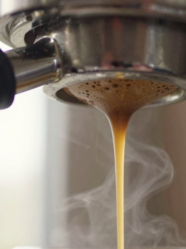 Close-up macro shot of rich, golden espresso dripping from a bottomless portafilter, warm morning window light, steam rising, shallow depth of field.