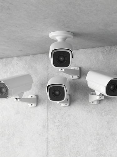Straight-on medium shot of modern HD security cameras neatly mounted on a clean concrete wall, bright utility lighting, no humans, ultra-sharp details