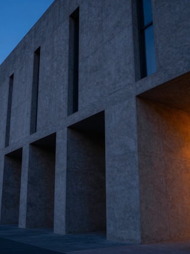 Wide-angle architectural shot of a modern concrete building facade with sharp geometric shadows, cool ambient blue twilight tones with a warm orange light leak on the right, 35mm lens