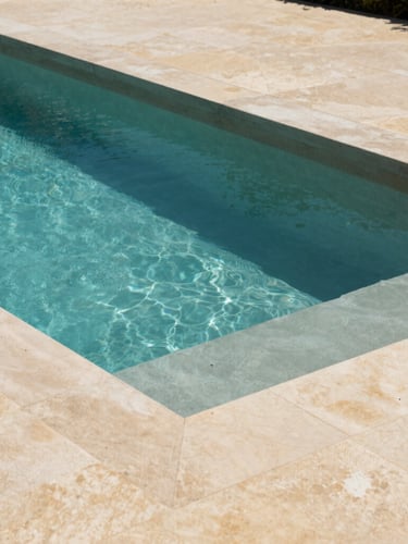 Architectural photography of a minimalist rectangular concrete swimming pool under bright Var sunlight, natural stone coping, turquoise water contrasting with warm beige stone deck.