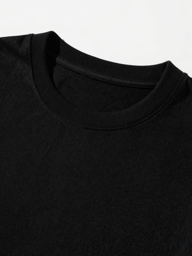 Sharp close-up studio photograph of a structured black T-shirt collar, direct sunlight casting sharp shadows on heavy cotton fabric texture.