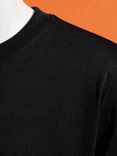 Extreme close-up of a structured black T-shirt collar and shoulder seam, highlighting the dense fabric texture, direct sunlight, 35mm lens.