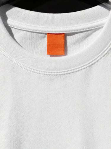 Extreme close-up of a washed white T-shirt collar showing intact high-density stitching and structured shape, direct sunlight