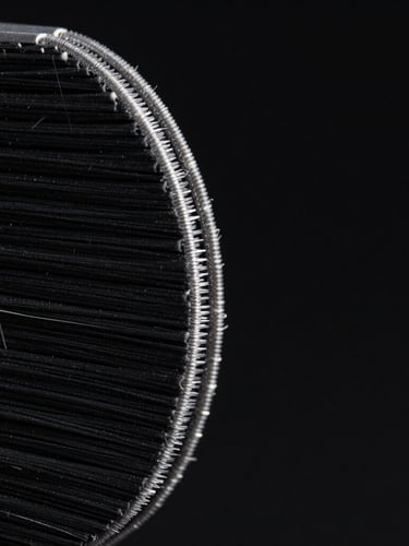 Extreme macro close-up of raw black aramid fiber case edge, sharp rim lighting, deep black background, ultra-detailed studio product photography