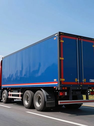 Low-angle heroic shot of a clean blue and red heavy-duty semi-truck trailer box driving on a bright Indonesian highway, clear daylight, high contrast