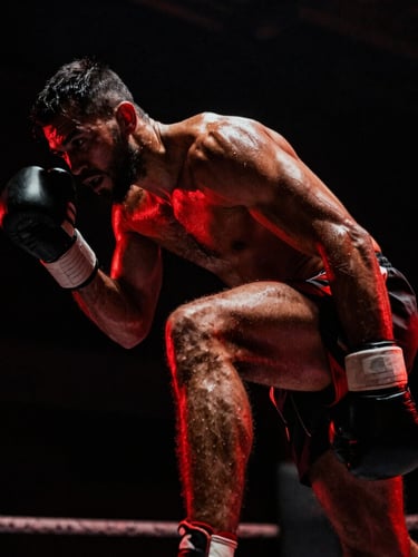 Gritty athletic photography of a fighter mid-dodge, high-contrast low-key lighting, sweat-glistening skin, dramatic crimson rim light, 35mm film