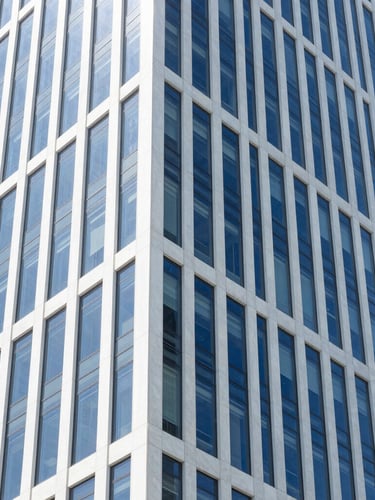 Crisp architectural photo of a modern high-rise office interior, clean glass walls, bright natural daylight, deep blue and white tones, sharp focus