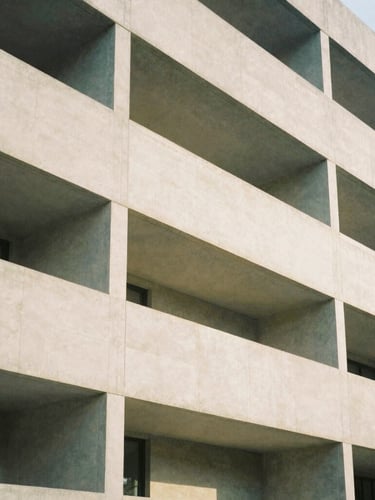 Abstract architectural lines of a modern concrete building facade, soft diffused daylight, warm neutral tones, 35mm