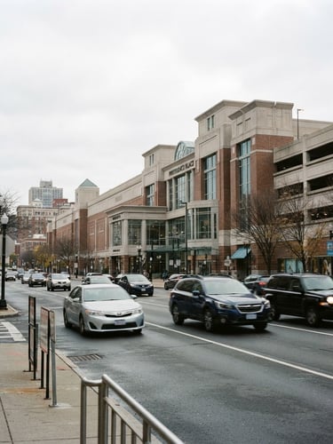 Bright natural daylight shot of cars driving past the Providence Place mall, realistic New England overcast sky, clean editorial photography, 35mm lens
