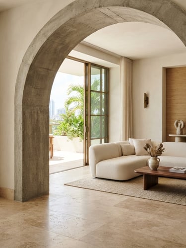 Warm architectural photography of a bright modern Miami interior with a concrete archway and neutral stone floor, natural daylight, medium format, sharp focus