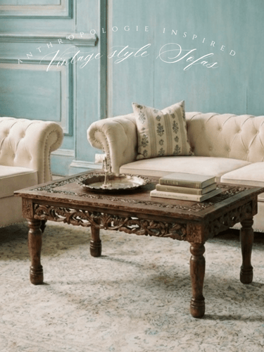 Vintage style tufted cream sofas and a carved wood coffee table in a rustic blue living room.